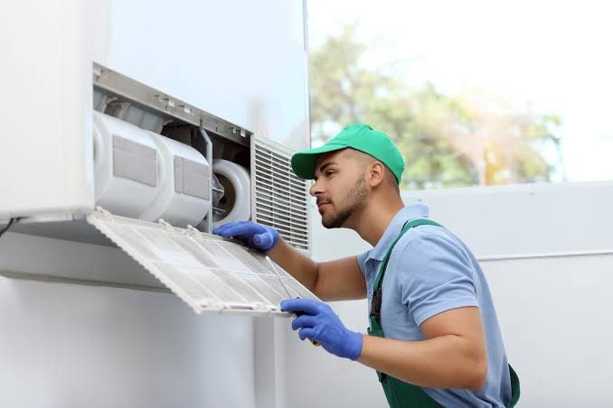 Technician checking a wall-mounted heating and cooling unit filter