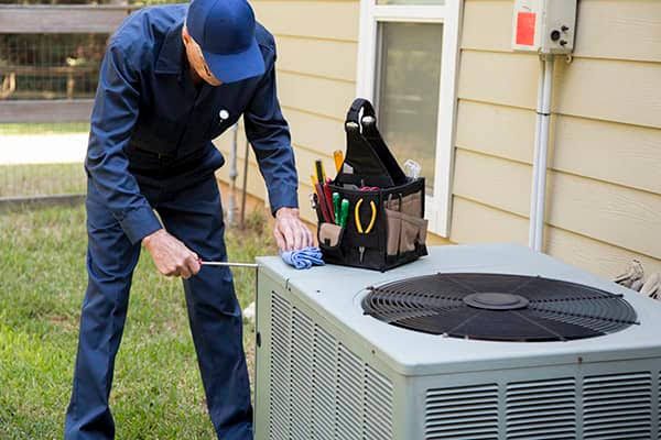 Technician servicing a residential outdoor air-conditioning condenser