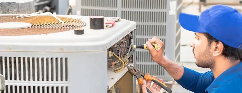 Technician repairing the electrical panel of an outdoor HVAC condenser