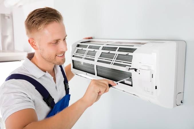 Technician inspecting the interior of a wall air-conditioning unit